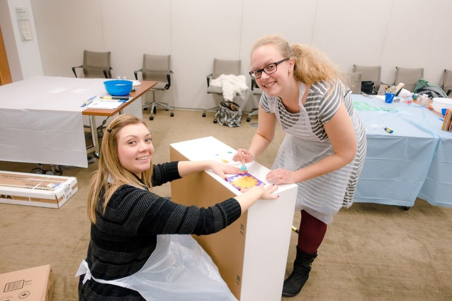 two colleagues assembling bookshelves for kids with a bookworm builders team building activity